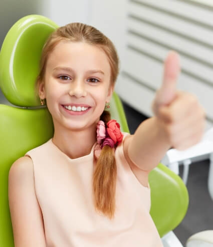 Young girl giving thumbs up while visiting children's dentist in Melbourne