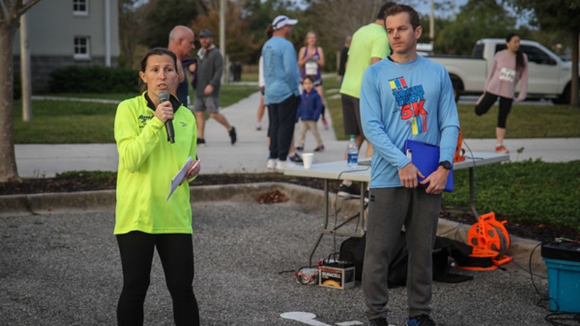 Woman in neon jacket speaking into microphone at 5 K race