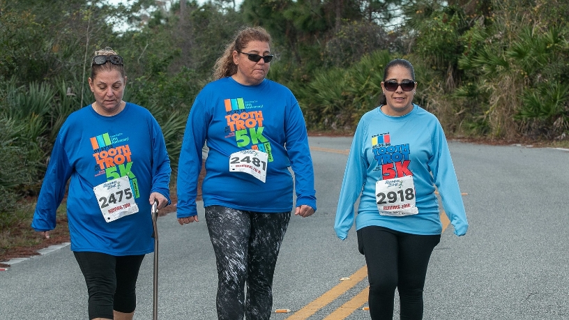 Three dental team members walking side by side during 5 K race