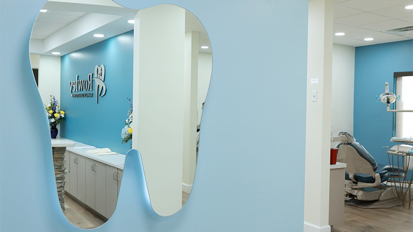 Tooth shaped mirror on light blue hallway of dental office