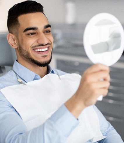 Patient smiling at reflection in handheld mirror