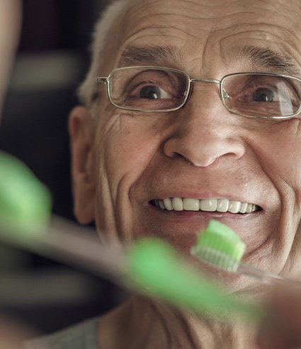 Patient in Melbourne smiling while brushing dentures 