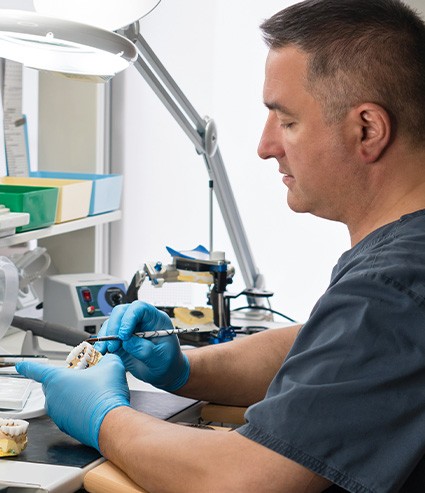A dental technician in Melbourne crafting a custom denture in a lab