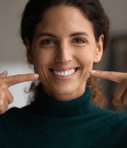 a woman pointing to her smile