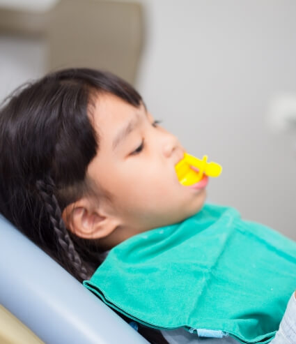 Young girl receiving fluoride treatment in dental office