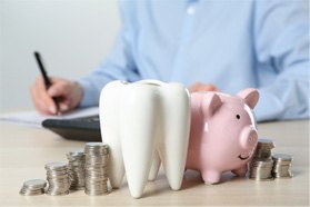 A large model tooth sitting next to a piggy bank and coins