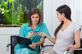 A woman paying the cost of cosmetic dentistry