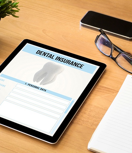 Dental insurance form on tablet next to office supplies