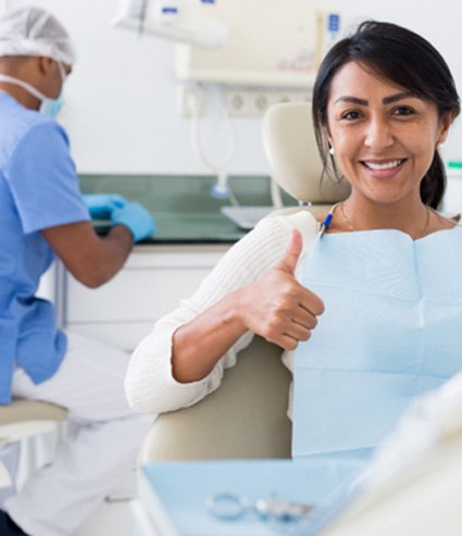 smiling woman in a dentist’s office giving a thumbs up