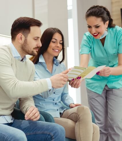 Dental team member showing two patients a pamphlet