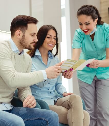 Dental team member showing two patients a pamphlet