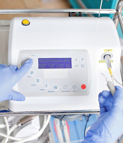 Gloved hands preparing to use dental laser