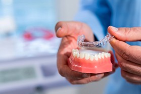 Dentist placing demonstration Invisalign over model teeth
