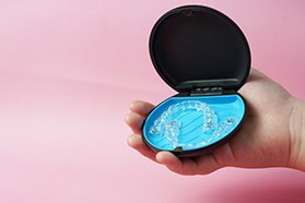 Hand holding carrier case with Invisalign inside
