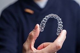 Dentist in navy blue scrubs holding Invisalign