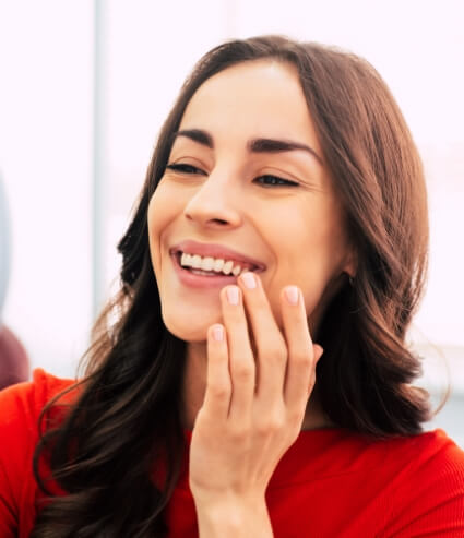 Young woman touching her face while looking in mirror