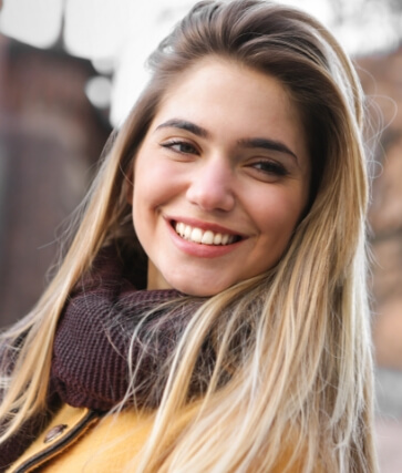 Blonde woman in scarf grinning outdoors