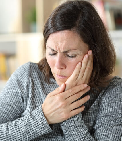 Woman holding her jaw in pain before T M J treatment in Melbourne