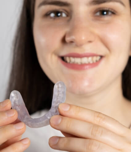 Woman holding an occlusal splint for T M J treatment