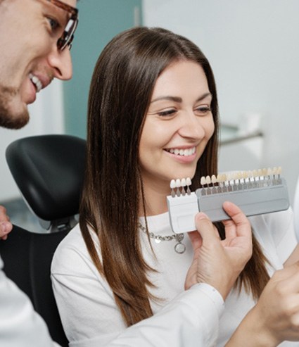 Dentist helping smiling patient select shade of veneer