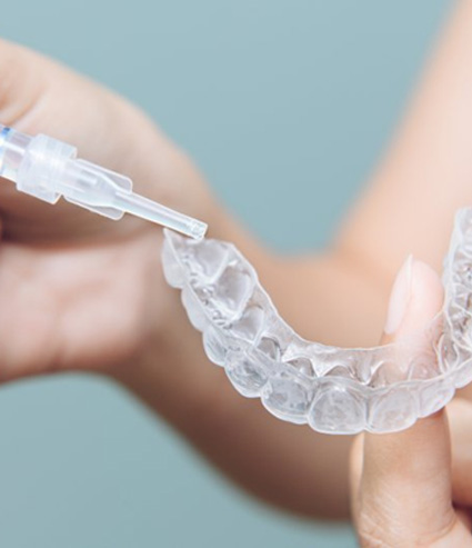 Patient applying whitening agent to whitening tray