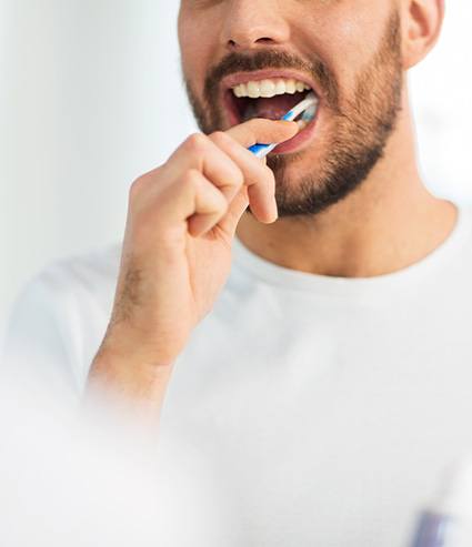 Closeup of man in white shirt brushing his teeth