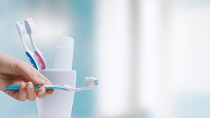 Holding toothbrush with toothpaste in front of a cup